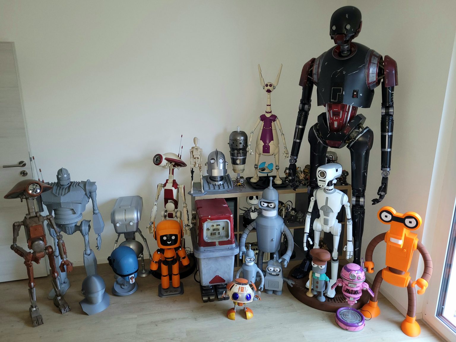 A corner of Rainer’s home office filled with printed droids and robots, from a full-size K-2SO down to desk-sized builds.
