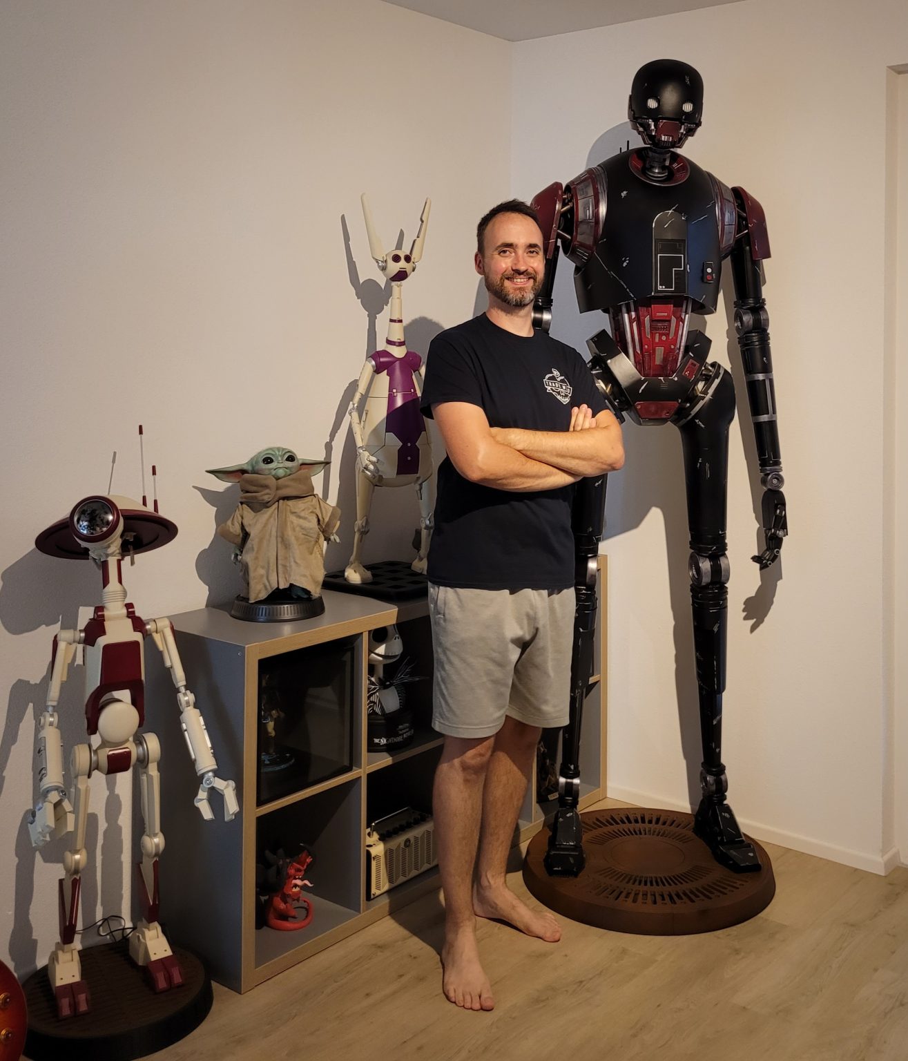 Rainer standing beside his full-size K-2SO build, with a battle droid, Grogu and other printed figures around him.